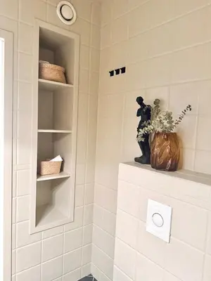 a white tiled shower with a vase of flowers on a shelf at Nice apartment super central at Solsiden in Trondheim