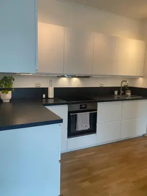 a kitchen with white cabinets and a black counter top at Nice apartment super central at Solsiden in Trondheim