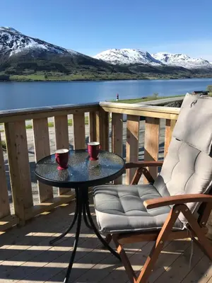 a table and a chair on a deck with a lake at Strand farm, sea view and boat rental in Averoy