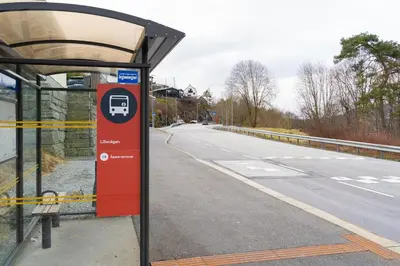 a bus stop with a red on the side of a road at Small house close to nature and city in Bergen