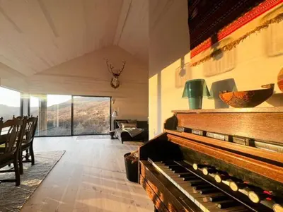 a living room with a piano in the middle of a room at New Cabin With Panoramic Views At Hardangervidda in Eidfjord