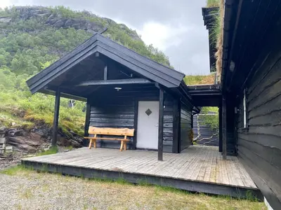 a cabin with a bench on a wooden deck at Nice cottage in quiet surroundings, surrounded by beautiful nature, near Gullingen in Gullingen