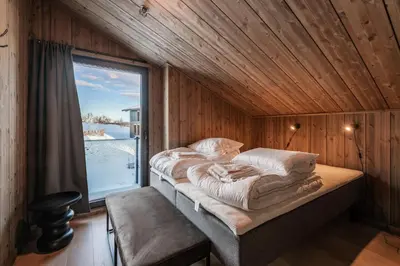 a bed in a wooden room with a window at Kikut Alpin Lodge 1302 in Geilo