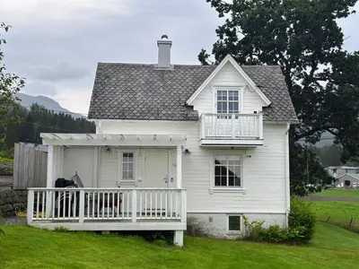a white house with a porch and a horse on the porch at Koselig vestlandshus ved fjorden in Holmedal
