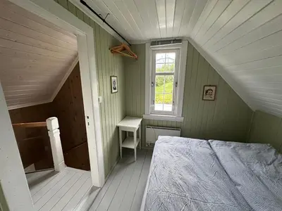 an attic bedroom with a bed and a window at Koselig vestlandshus ved fjorden in Holmedal