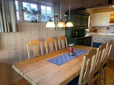a kitchen with a wooden table and some chairs at Koselig og sentral hytte med peis og badstue in Beitostøl