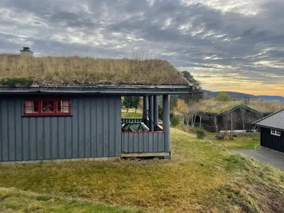 a house with a grass roof with a window at Koselig og sentral hytte med peis og badstue in Beitostøl