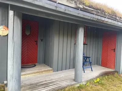 a porch of a house with red doors and a blue chair at Koselig og sentral hytte med peis og badstue in Beitostøl