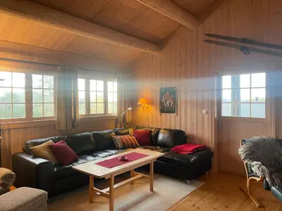 a living room with a leather couch and a table at Koselig og sentral hytte med peis og badstue in Beitostøl