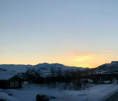 a house in the snow with the sunset in the background at Apartment With Panoramic Views In Beitostølen in Beitostøl