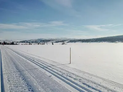 a snowy road with tire tracks in the snow at Log Cabin By Mostertoppen Ski Stadium in Øyer