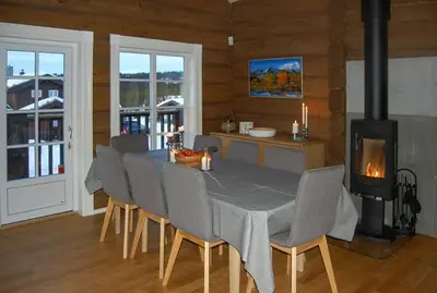 a dining room with a table and chairs and a stove at Log Cabin By Mostertoppen Ski Stadium in Øyer