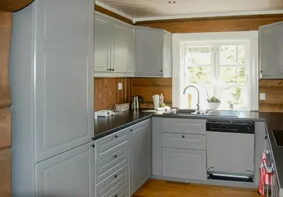 a kitchen with white cabinets and a sink and a window at Log Cabin By Mostertoppen Ski Stadium in Øyer