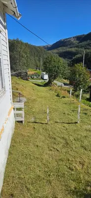 a grassy yard with a white fence next to a house at Retro & Vintage Camping in Vaksdal