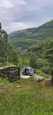 a van parked in a field with mountains in the background at Retro & Vintage Camping in Vaksdal