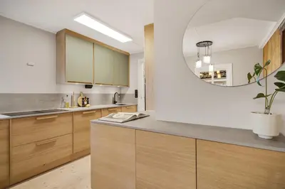 a kitchen with wooden cabinets and a round mirror at THIS IS BERGEN, 2 min walk to everything in Bergen