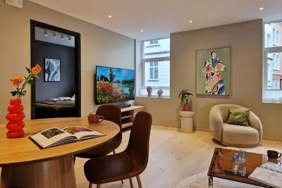 a living room with a table and chairs and paintings at Brand New & High-End 3 Bedrooms 2 Bathrooms Central Apartment in Bergen