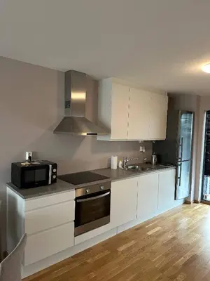 a kitchen with white cabinets and a black microwave at Apartament Near Haugesund in Skred