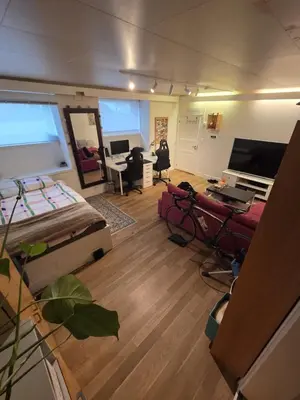 a living room with a bed and a piano at Big and cozy room in the middle of the city in Trondheim