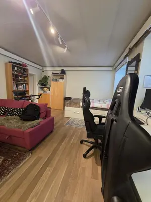 a living room with a couch and a chair and a desk at Big and cozy room in the middle of the city in Trondheim