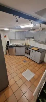 a kitchen with white cabinets and a tiled floor at Big and cozy room in the middle of the city in Trondheim