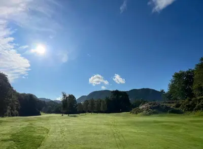 a large green field with mountains in the background at Villa med 5 soverom, 4 bad og 3 kjøkken, 400 m fra lokal badestrand in Bergen