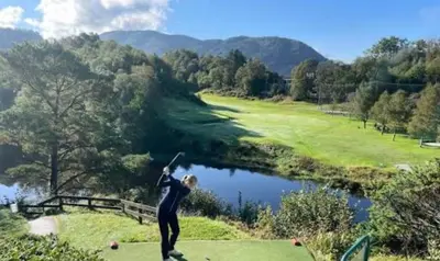 a woman standing on a golf course with her arms in the air at Villa med 5 soverom, 4 bad og 3 kjøkken, 400 m fra lokal badestrand in Bergen