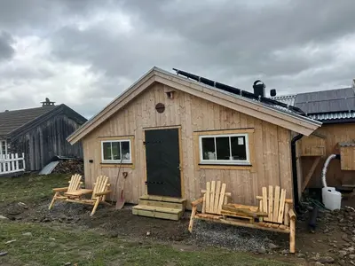 a small wooden house with two chairs and a door at Bottheimsætra
