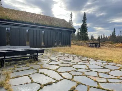 a building with a bench next to a stone patio at Moderne storhytte med 5 soverom og 3 bad in Beitostøl