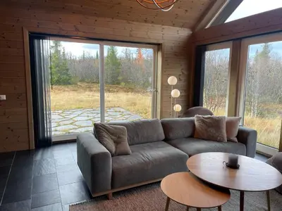 a living room with a couch and a table at Moderne storhytte med 5 soverom og 3 bad in Beitostøl