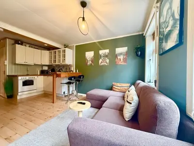 a living room with a purple couch and a kitchen at Rustic Retreat Apartment, Central & free parking ! in Trondheim