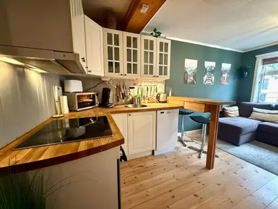 a kitchen with white cabinets and a couch in a living room at Rustic Retreat Apartment, Central & free parking ! in Trondheim