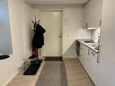 a small kitchen with white cabinets and a door at Modern Apt - Steps from Grieghallen and Trainstation in Bergen
