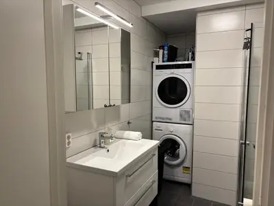 a bathroom with a sink and a washing machine at Modern Apt - Steps from Grieghallen and Trainstation in Bergen