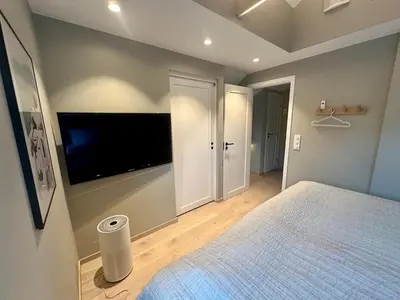 a bedroom with a large bed and a flat screen tv at Spacious, central 3 BR house with parking in Bergen