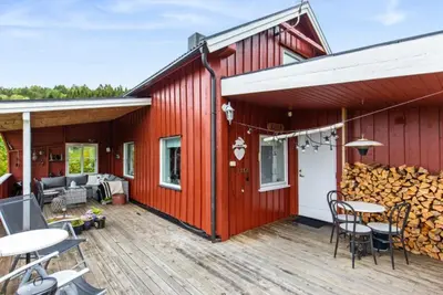 a red house with a deck with tables and chairs at Kvila in Tingvoll