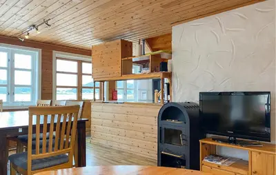 a living room with a television and a stove at Gorgeous Home In Leinøy With House Sea View in Fosnavåg