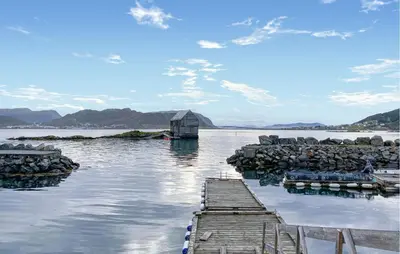 a dock in a body of water with a house at Gorgeous Home In Leinøy With House Sea View in Fosnavåg