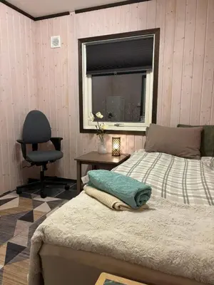 a bedroom with a bed and a chair and a window at Koselig rom i studentfelleskap