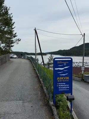 a sign on the side of a road near a body of water at Askvik Marina Lägenhet i småbåtshamn med havsutsikt