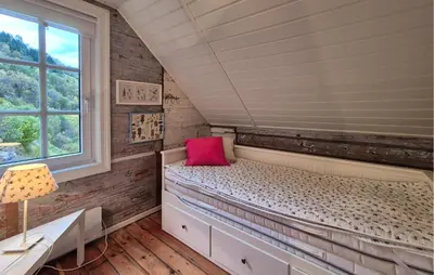 a bedroom with a bed with a pink pillow at Beach Front Home In Vaksdal With House Sea View in Vaksdal