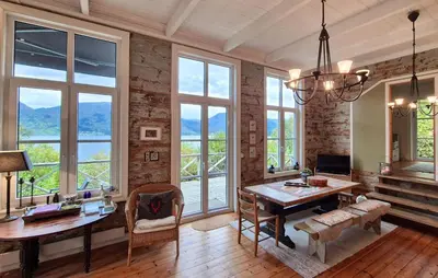 a living room with a table and some windows at Beach Front Home In Vaksdal With House Sea View in Vaksdal