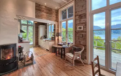 a living room with a fireplace and a table and chairs at Beach Front Home In Vaksdal With House Sea View in Vaksdal