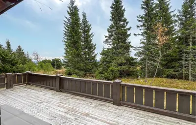 a wooden deck with a fence and trees at Lovely Home In Sjusjøen With Sauna in Sjusjøen