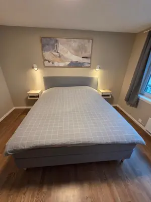 a bed in a bedroom with two lights on both sides at Kristiansund Luxury Apartment in Kristiansund