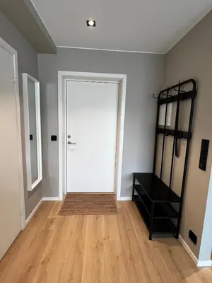 an empty room with a white door and wooden floors at Newly refurbished apartment in the city center in Verdal