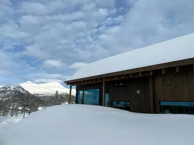 a building covered in snow with mountains in the background at Modern Family Cabin By The Ski Trail In Tuddal in Tuddal