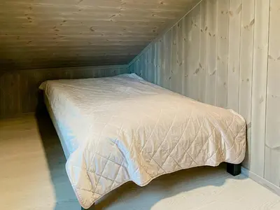 a bed in a room with a wooden wall at Modern Family Cabin By The Ski Trail In Tuddal in Tuddal