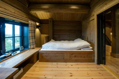 a bed in a wooden room with a window at Handcrafted Log Cabin At Golsfjellet in Gol