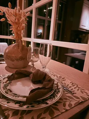 a table with a plate and wine glasses on it at Nikolaisens Nordic Panorama hideaway in Stranda